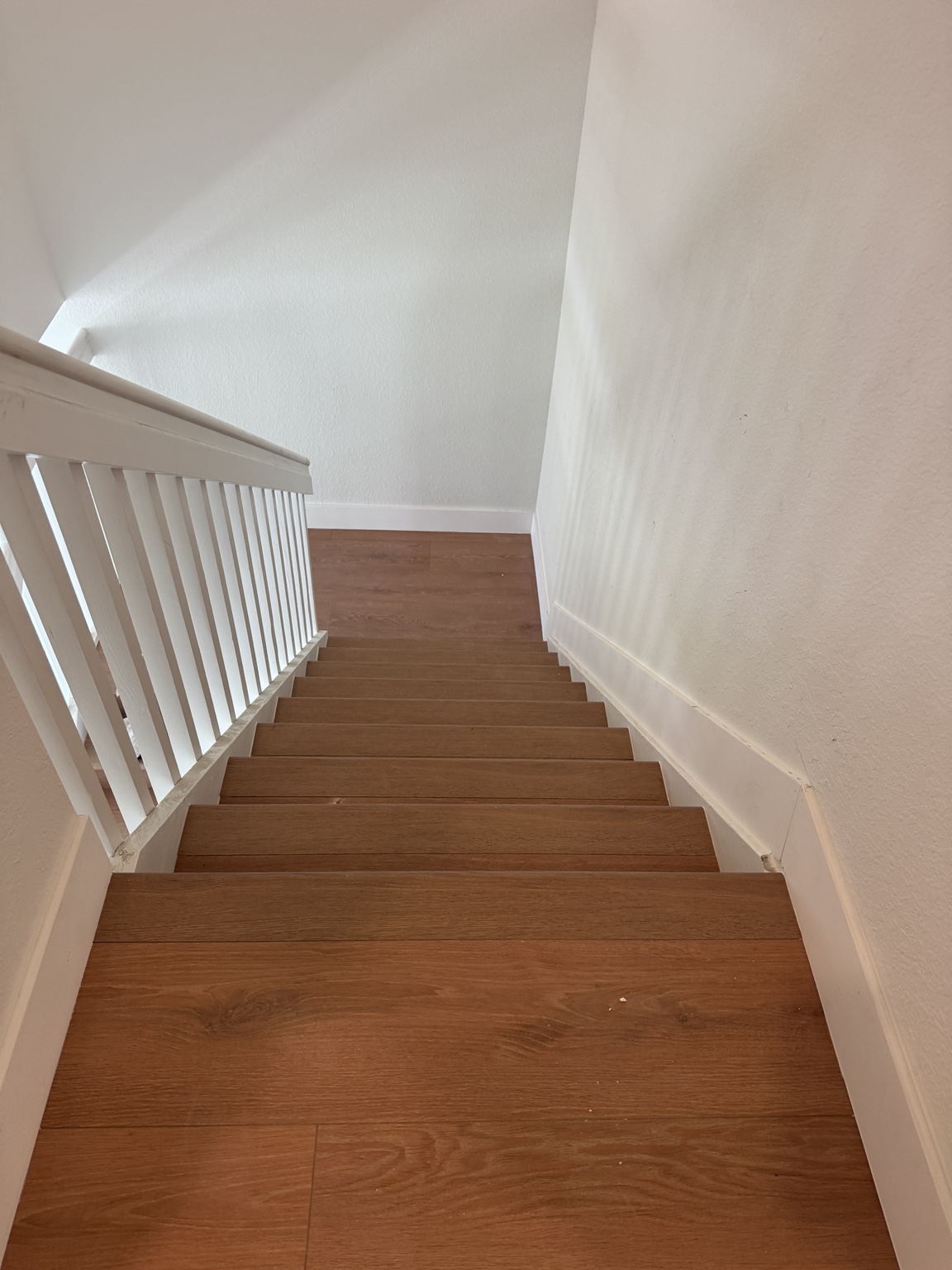 Top-landing view of finished staircase in warm oak laminate finish