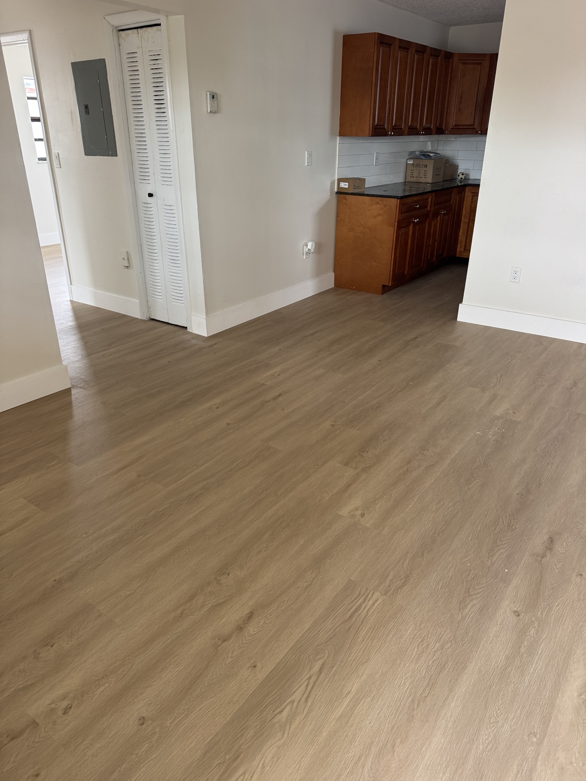 Living and dining area finished with light wood-look waterproof vinyl flooring, continuous into the kitchen.