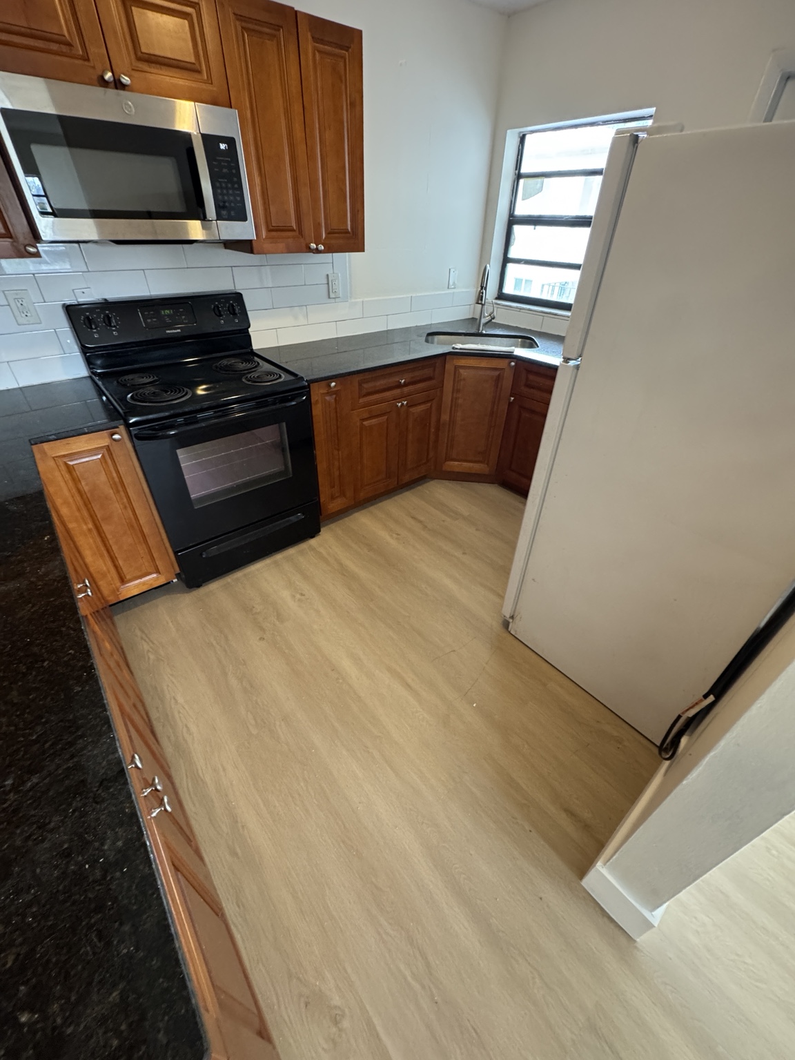 Kitchen after installation of light wood-look waterproof vinyl flooring.