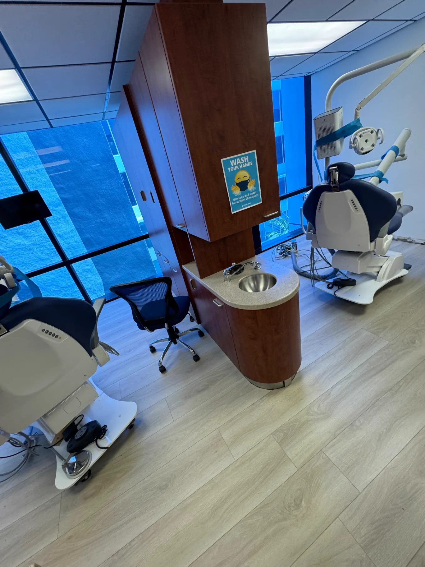 Wide view of the completed two-chair dental operatory in Miami showing the continuous commercial wood-look flooring installed by Colors Wood Floor Corp.