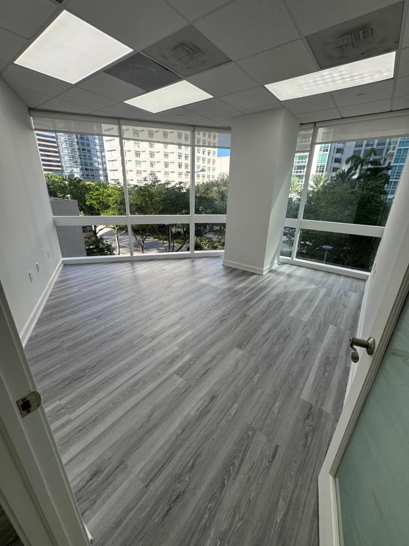 Commercial office flooring installed by Colors Wood Floor Corp in a Brickell corner office with city views, Miami