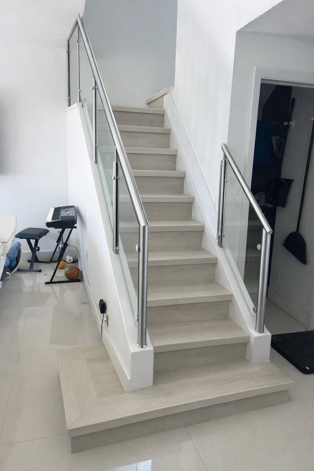 Completed staircase with extended first step and modern finish; railing by others.